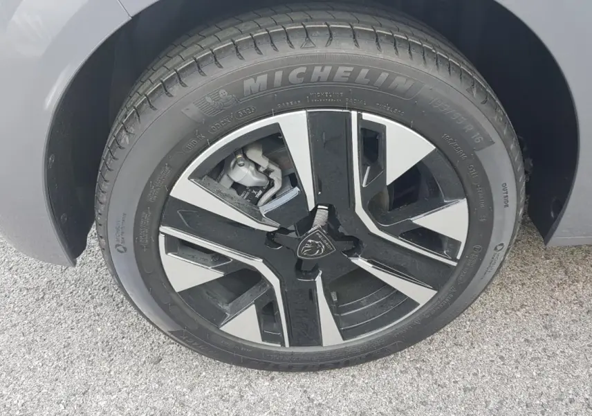 Gros plan sur la roue avant droite gris métallisé d'une Peugeot 208 Hybrid 110 e-DCS6 Allure avec jante alliage noire et argent.