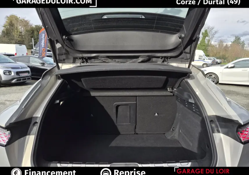 Coffre ouvert vu de l'arrière d'une DS4 beige 2024, montrant un espace de rangement spacieux et noir.