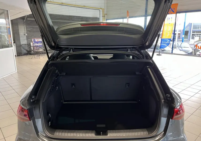 Coffre ouvert d'une Audi A3 Sportback gris, vue arrière intérieure montrant l'espace de chargement vide.