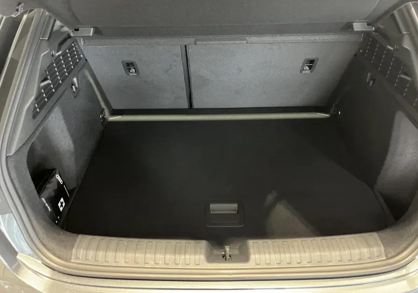 Coffre ouvert d’Audi A3 Sportback gris, vue de dessus montrant l’espace de chargement et une trousse de secours à gauche.