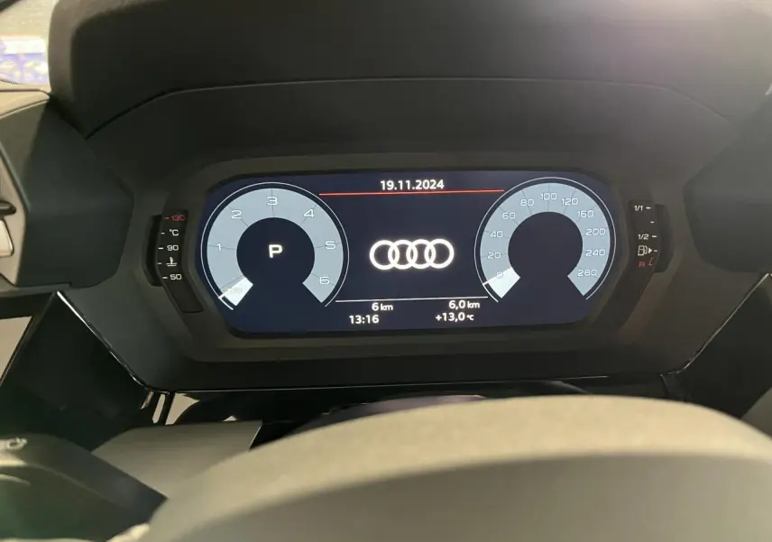 Vue rapprochée du tableau de bord numérique de l'Audi A3 Sportback gris, affichant les compteurs et logo Audi central.