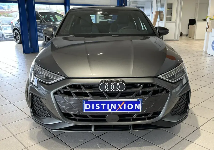Vue frontale d’une Audi A3 Sportback gris métallisé 2025 avec calandre S line et phares LED dynamiques en showroom.