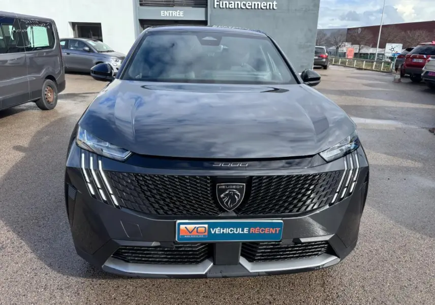Vue de face du Peugeot 3008 Hybrid gris 2025 avec calandre noire et feux LED verticaux allumés.