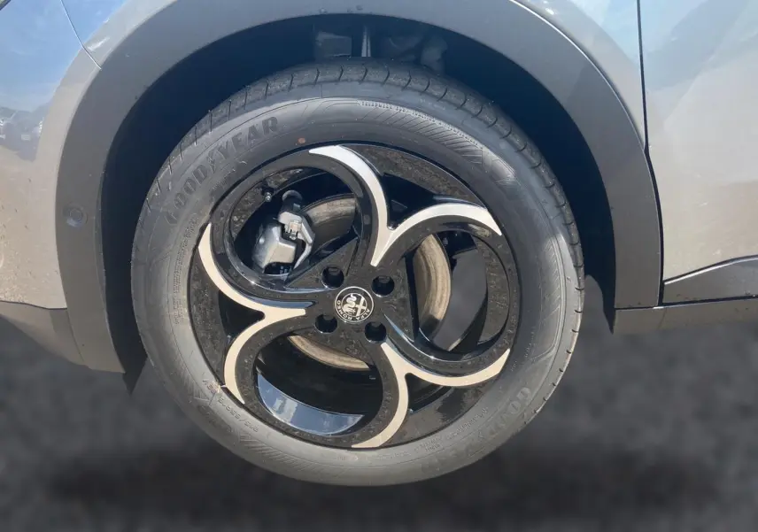 Gros plan sur la roue arrière droite gris métallisé d'une Alfa Romeo Junior 1.2 hybride avec jante alliage noire et argent.