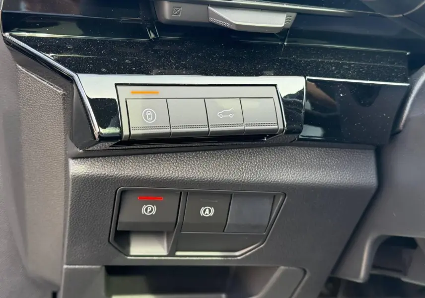 Gros plan sur les boutons de commande du tableau de bord du Renault Austral 1.2 E-Tech gris, avec éclairage LED rouge et orange.