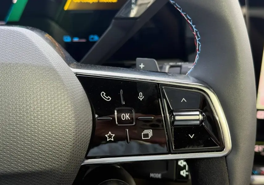 Gros plan sur les commandes multifonctions côté gauche du volant du Renault Austral gris Schiste satin avec surpiqûres tricolores.