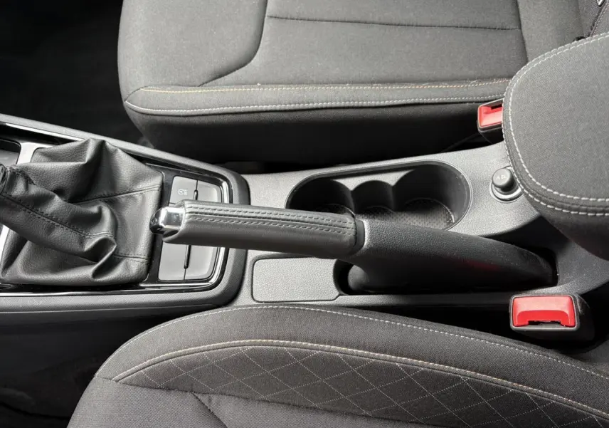 Vue plongeante sur la console centrale du Skoda Kamiq 2024, montrant frein à main manuel et sièges tissu noirs.
