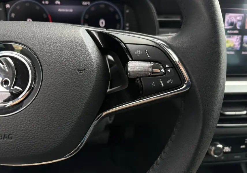 Gros plan sur le volant cuir noir multifonctions côté droit du Skoda Kamiq 2024 avec commandes intégrées et tableau de bord numérique.