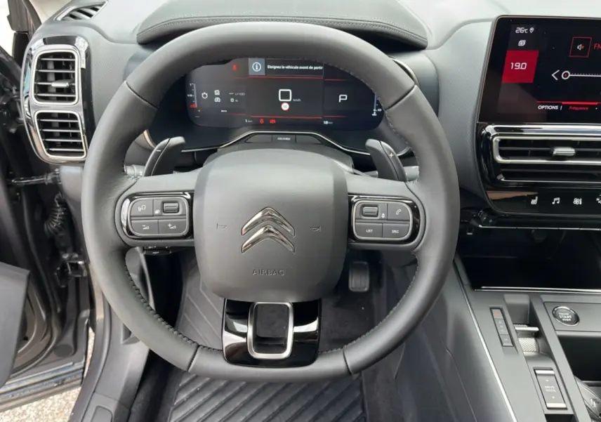 Vue intérieure centrée sur le volant multifonction du Citroën C5 Aircross Hybrid 2025 avec tableau de bord numérique.