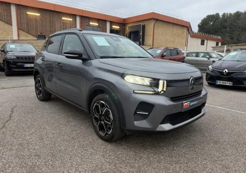 Vue 3/4 avant gauche d'une Citroën C3 Turbo 100 ch gris avec jantes alliage 17 pouces et barres de toit visibles.