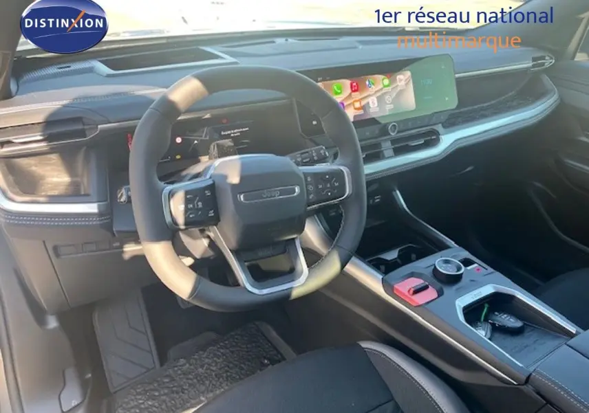 Vue intérieure du poste de conduite du Jeep Compass 2026, volant multifonction et écran tactile large, ambiance noire moderne.