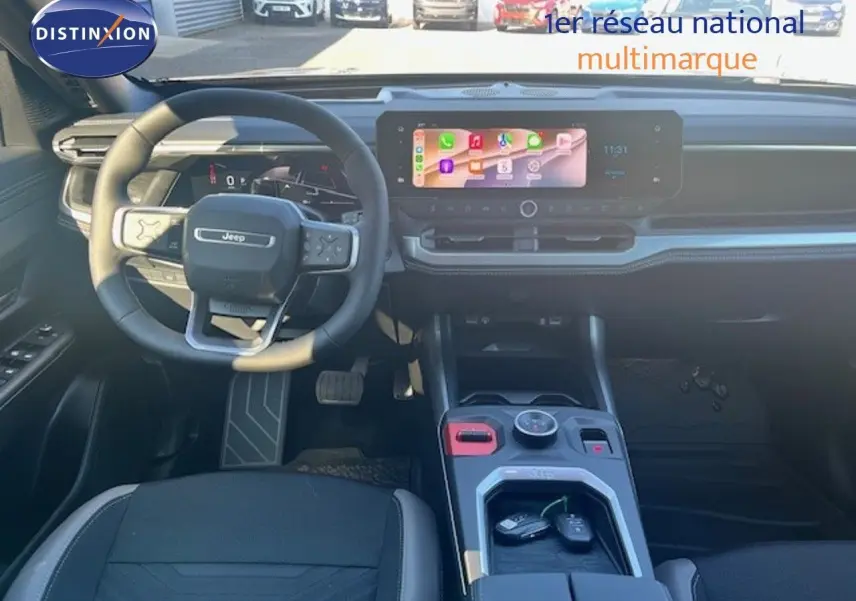 Intérieur Jeep Compass 2026 vue avant, tableau de bord noir avec écran tactile large et volant multifonction cuir.