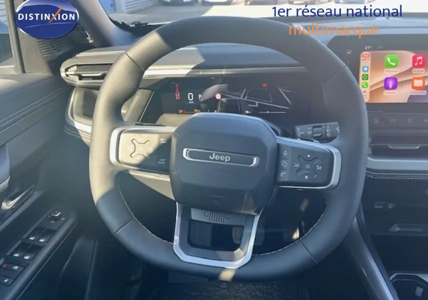 Vue intérieure centrée sur le volant Jeep noir avec tableau de bord numérique et écran tactile couleur.