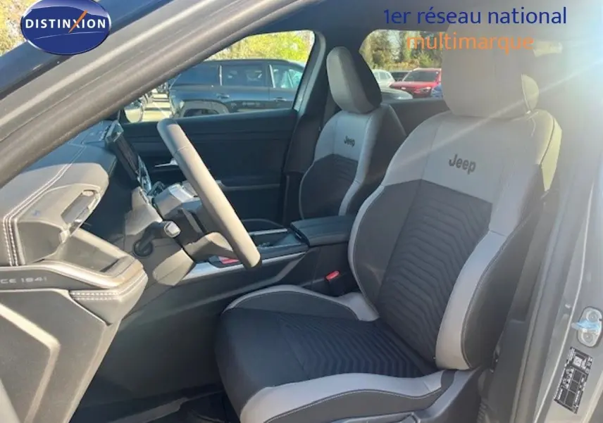 Vue intérieure côté conducteur du Jeep Compass 2026, sièges bi-ton gris et noir avec logo Jeep brodé.
