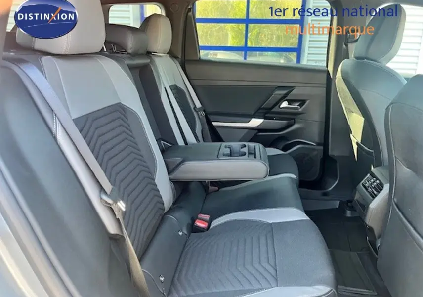 Vue intérieure arrière du Jeep Compass 2026, sièges bicolores gris et noir avec accoudoir central déployé.