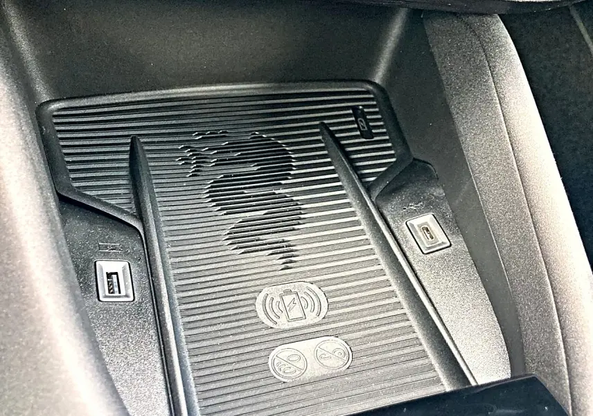 Détail du chargeur à induction noir avec logo serpent Alfa Romeo gravé, dans l’habitacle de l’Alfa Romeo Junior gris.