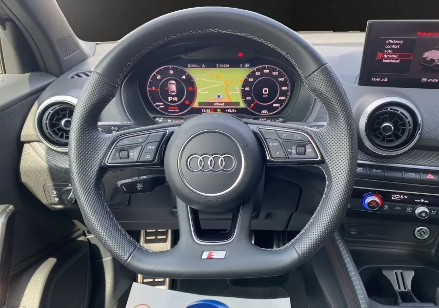 Vue rapprochée du volant sport en cuir perforé avec méplat et du tableau de bord numérique de l'Audi Q2 S line 2024.