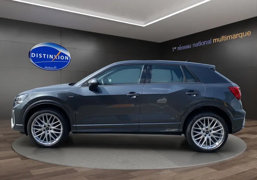 Audi Q2 gris Daytona en profil droit, avec jantes alu Audi Sport 19 pouces et finition S line visible sur l'aile avant.