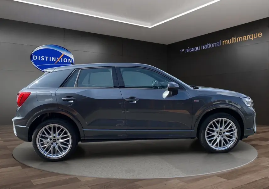 Audi Q2 S line gris Daytona en profil côté gauche, avec jantes aluminium 19 pouces et hayon électrique visible.