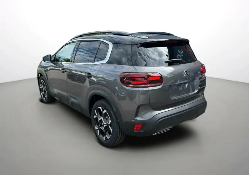 Vue 3/4 arrière droite du Citroën C5 Aircross 2025 gris platinium avec toit noir et jantes distinctives.