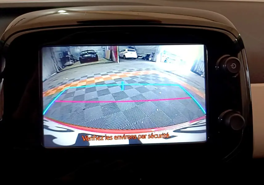 Vue écran caméra de recul d'une Peugeot 108 rouge, avec lignes de guidage colorées et message de sécurité en français.