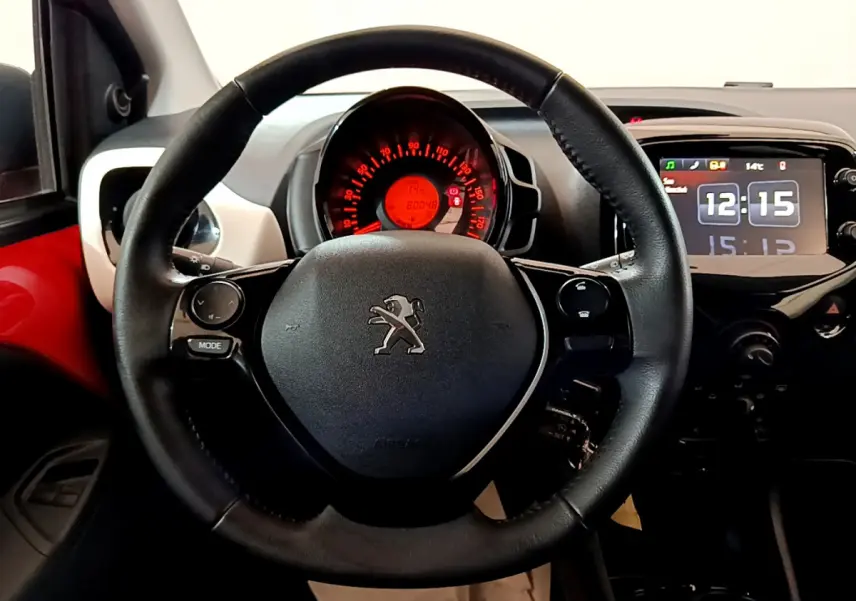 Vue rapprochée du volant cuir noir et du tableau de bord numérique de la Peugeot 108 rouge, version 2017.