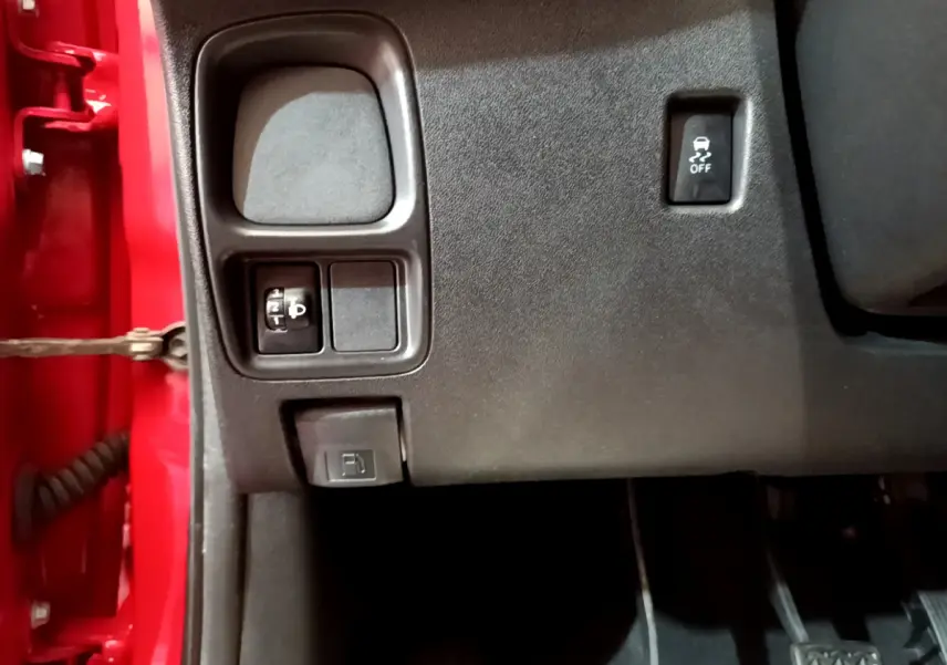 Vue rapprochée côté gauche sous le tableau de bord rouge du Peugeot 108 2017, avec commandes d'éclairage et traction.