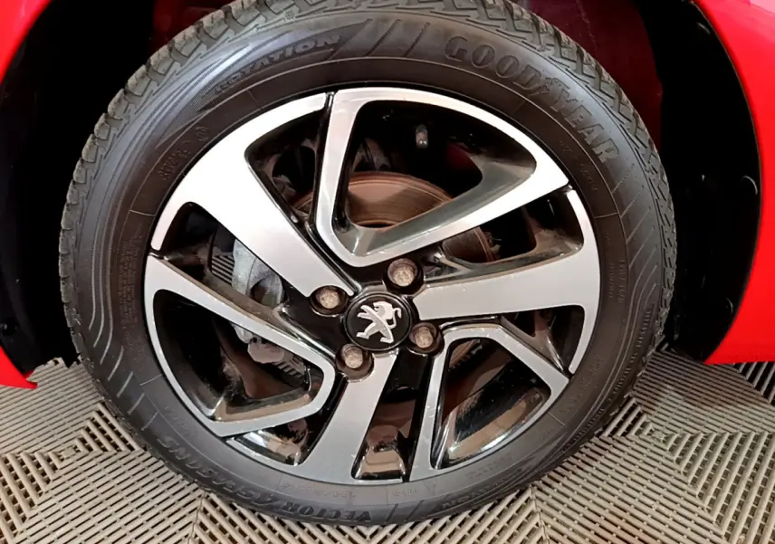 Gros plan sur la roue avant gauche rouge d'une Peugeot 108 2017 avec jante alliage et logo lion central.