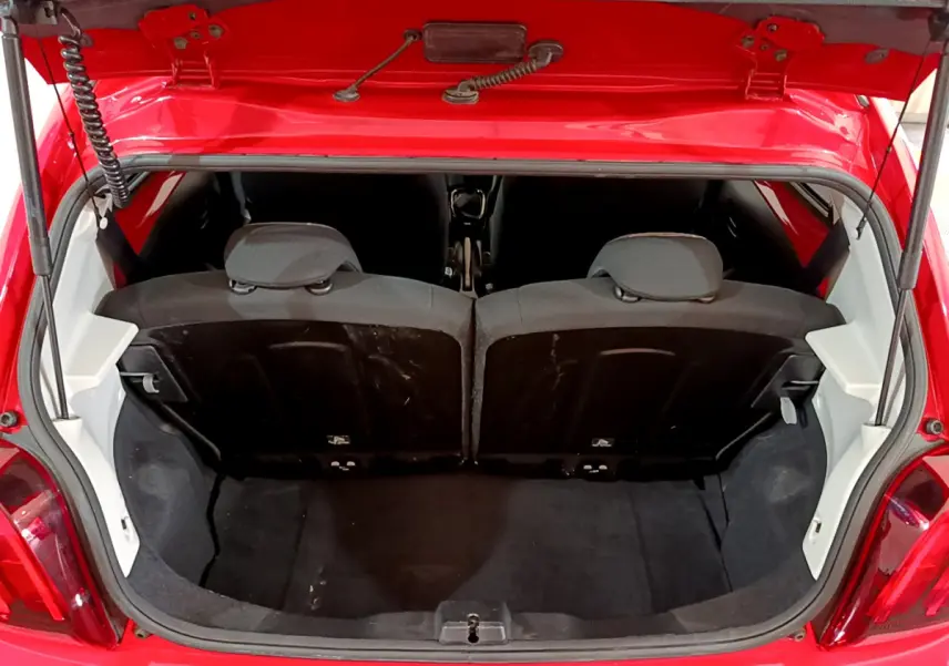Coffre ouvert vu de l'arrière d'une Peugeot 108 rouge, montrant la banquette arrière et l'espace de chargement.