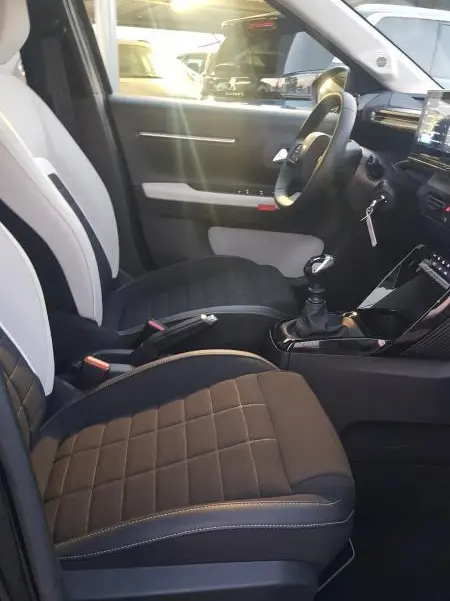 Vue intérieure côté conducteur de la Citroën C3 Turbo 100 ch 2025 noire, sièges bi-ton et boîte manuelle visible.