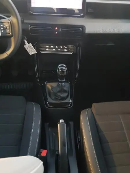 Vue intérieure centrée sur la console centrale d'une Citroën C3 noire 2025 avec boîte manuelle et écran tactile.