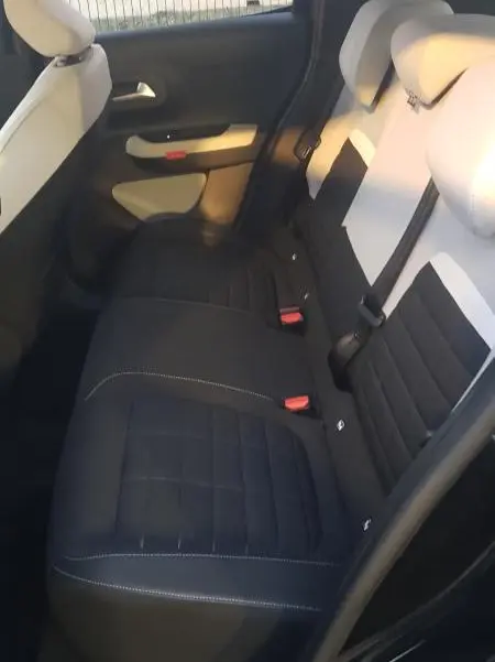 Vue intérieure arrière côté gauche de la Citroën C3 noire 2025, montrant les sièges arrière bicolores et les ceintures de sécurité.