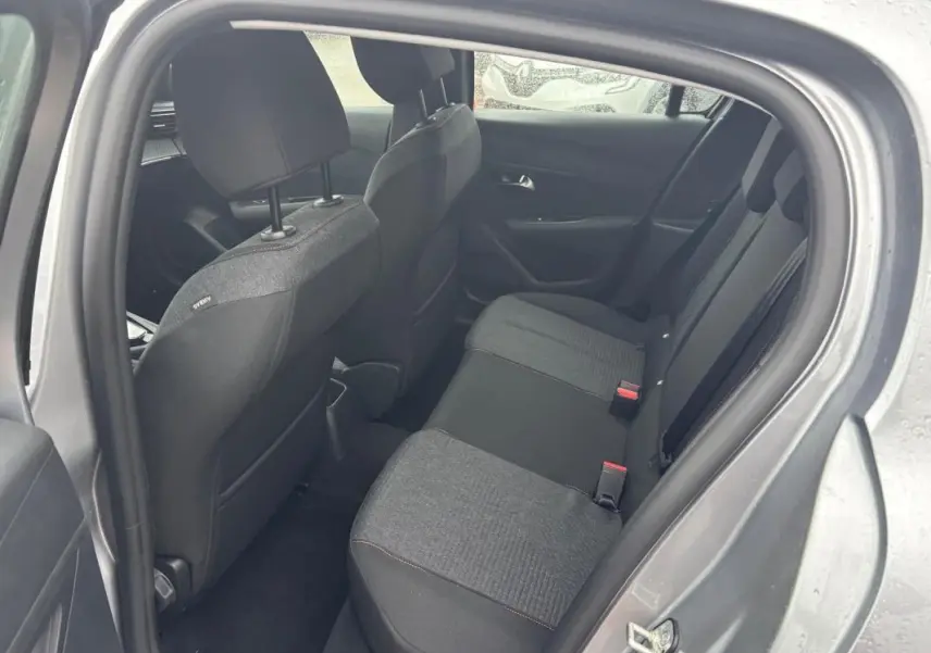 Vue intérieure côté droit des sièges arrière gris foncé d'une Peugeot 208 Hybrid 100 e-DCS6 Style 2025 avec portières ouvertes.