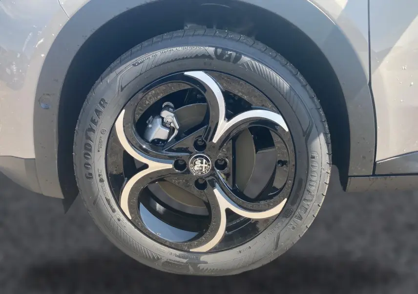Gros plan sur la jante en alliage noir et argentée côté gauche d'une Alfa Romeo Junior ivoire et noir.