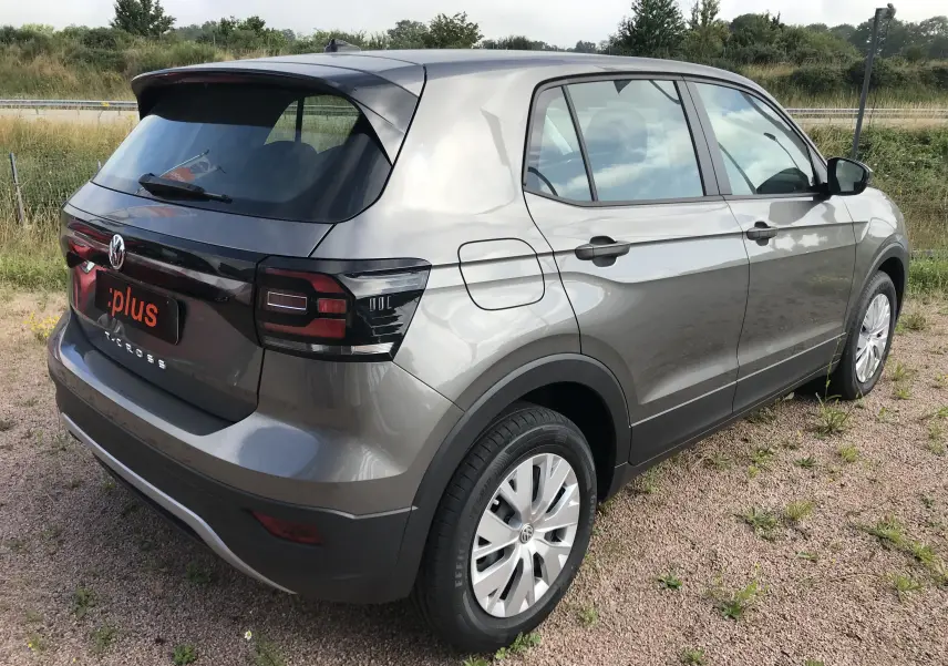 Vue 3/4 arrière droite d'un Volkswagen T-Cross gris Limestone 2020 avec feux arrière foncés et jantes argentées.
