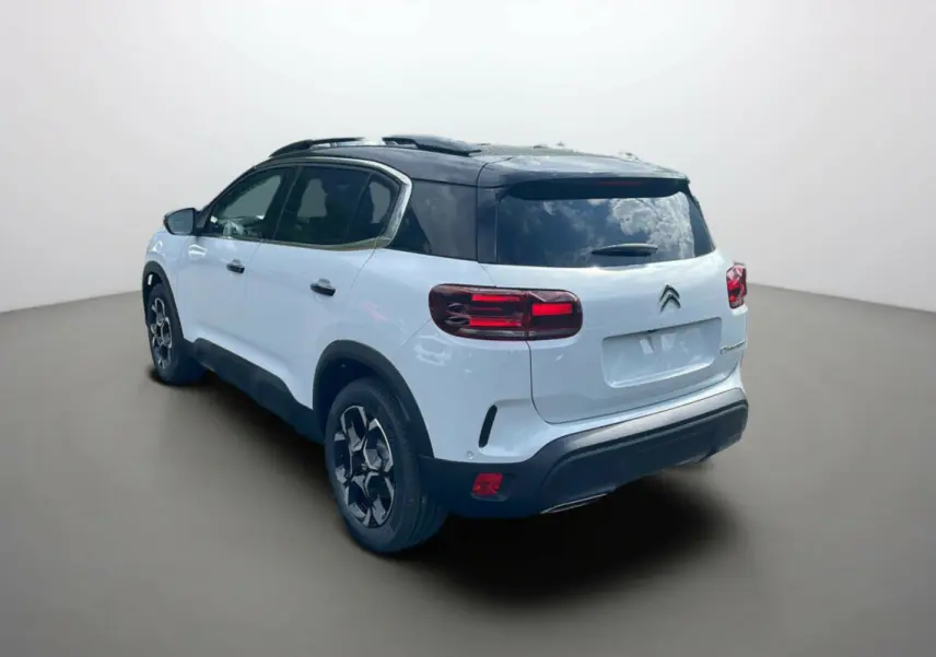 Vue 3/4 arrière gauche du Citroën C5 Aircross hybride 2025 blanc okénite avec toit noir et jantes stylées.