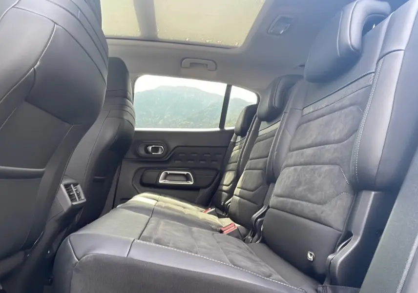 Vue latérale droite de l'intérieur arrière du Citroën C5 Aircross 2025, sièges en cuir noir avec toit panoramique.