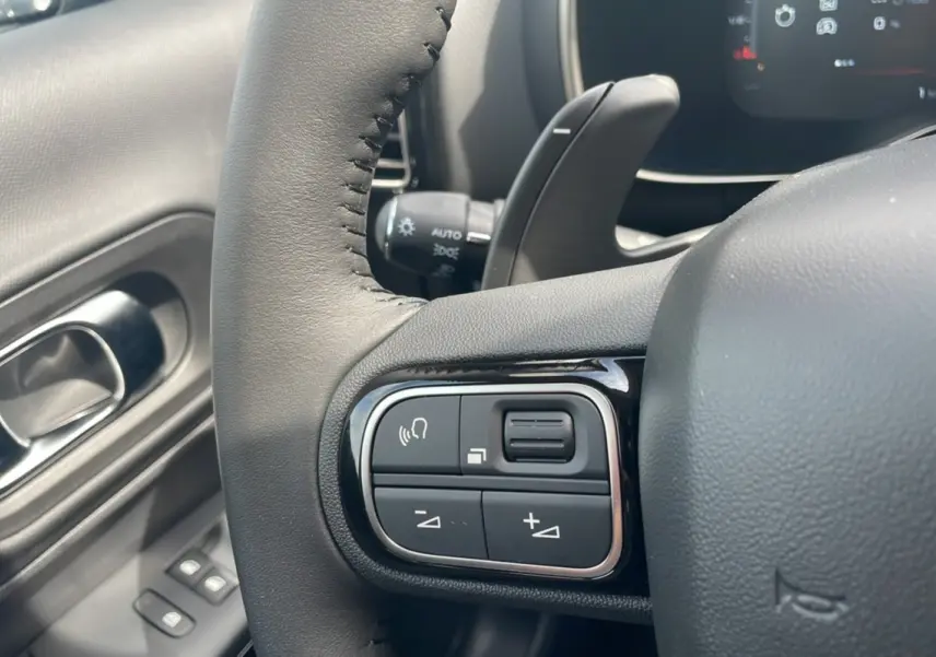 Gros plan sur les commandes du volant côté gauche du Citroën C5 Aircross Hybrid 2025 blanc avec toit noir.