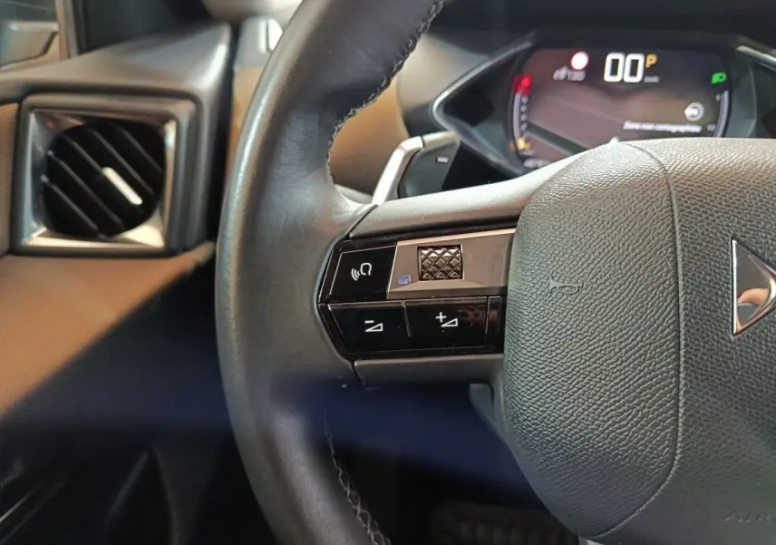 Gros plan sur le volant cuir noir côté gauche du DS3 Crossback 2020 avec commandes vocales et tableau de bord numérique.