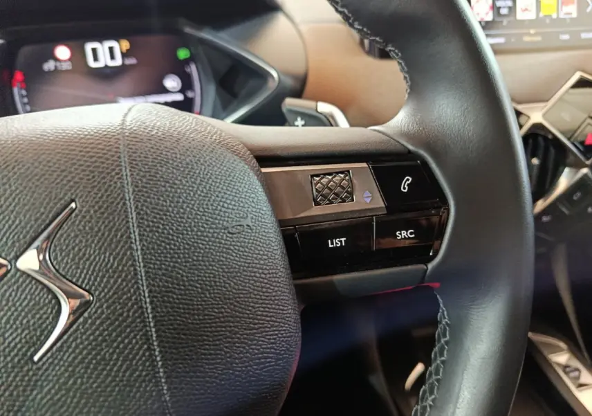Gros plan sur le volant cuir noir du DS3 Crossback 2020 avec commandes vocales et écran numérique en arrière-plan.