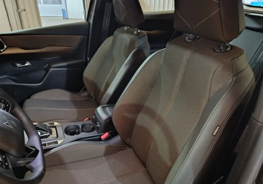 Vue intérieure côté gauche des sièges avant gris foncé du DS3 Crossback avec volant cuir et console centrale visible