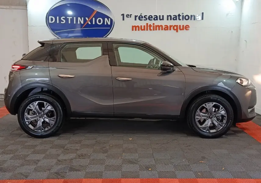 Profil côté gauche d'un DS3 Crossback gris foncé 2020, avec jantes alliage et poignées de porte intégrées au design.