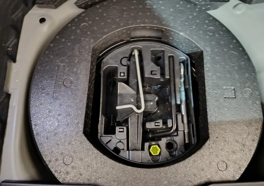 Gros plan sur la roue de secours galette et son kit d'outils dans le coffre du DS3 Crossback gris foncé.