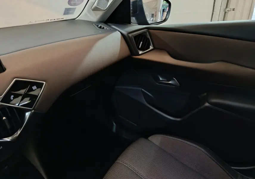 Intérieur côté passager du DS3 Crossback gris foncé, montrant la portière et le tableau de bord beige et noir.