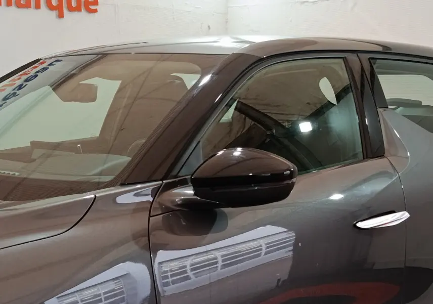 Vue de profil côté gauche sur la porte avant d'une DS3 Crossback gris foncé avec rétroviseur ton caisse brillant.