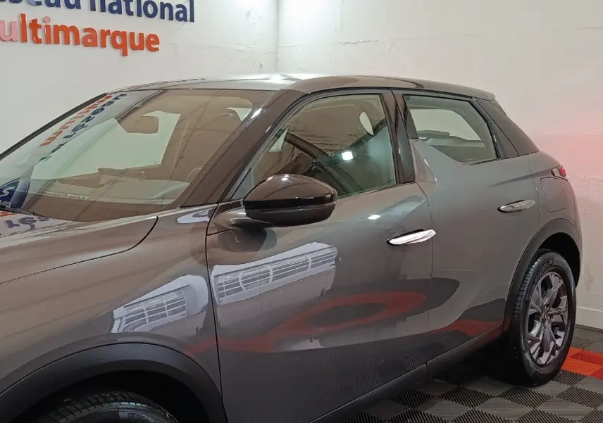 Vue côté gauche d'un DS3 Crossback gris foncé 2020 avec poignées chromées et jantes alliage.