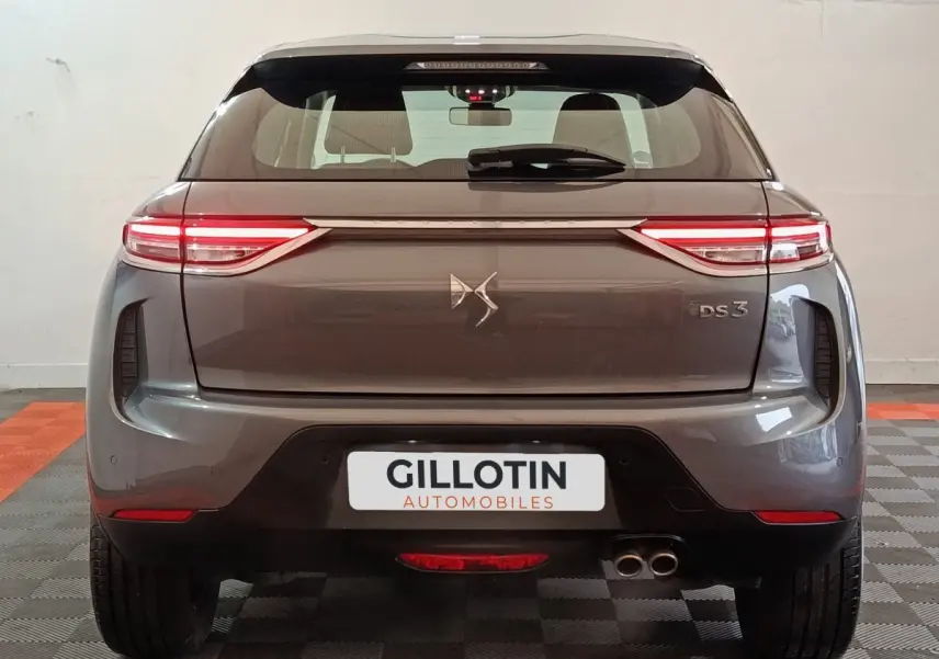 Vue arrière d'un DS3 Crossback gris foncé avec feux LED étirés et double sortie d'échappement visible à droite.