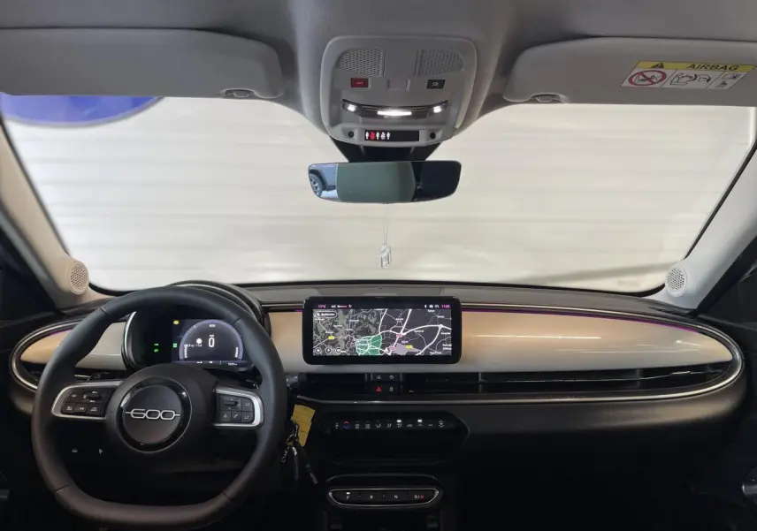 Tableau de bord beige métallisé de la FIAT 600 1.2 Hybrid 2025 avec écran tactile et volant multifonction.