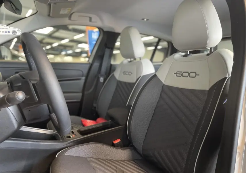 Intérieur du FIAT 600 beige métallisé, vue côté conducteur sur les sièges avant bicolores avec logo 600 brodé.