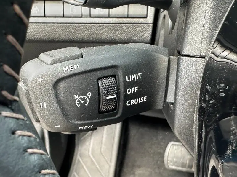 Gros plan sur la commande de régulateur de vitesse du Peugeot 3008 Hybride Rechargeable bleu, côté gauche du volant.